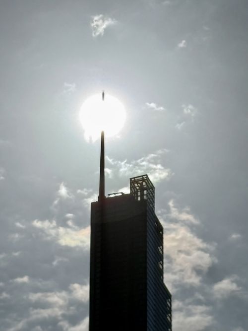 The top of the Herron Tower in London. The sun sits right behind the tower’s spire and appears to pierce it.